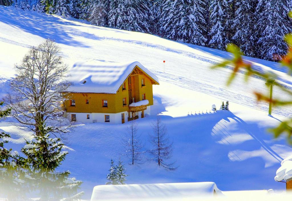 a house on a snow covered hill with snow at Appartement Doris in Schröcken