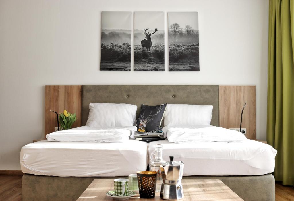 2 Betten mit weißer Bettwäsche und ein Hirschgemälde an der Wand in der Unterkunft Seelos - Alpine Easy Stay - Bed & Breakfast in Mieming