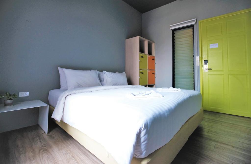 a bedroom with a large white bed and a yellow door at iSanook Hostel in Bangkok