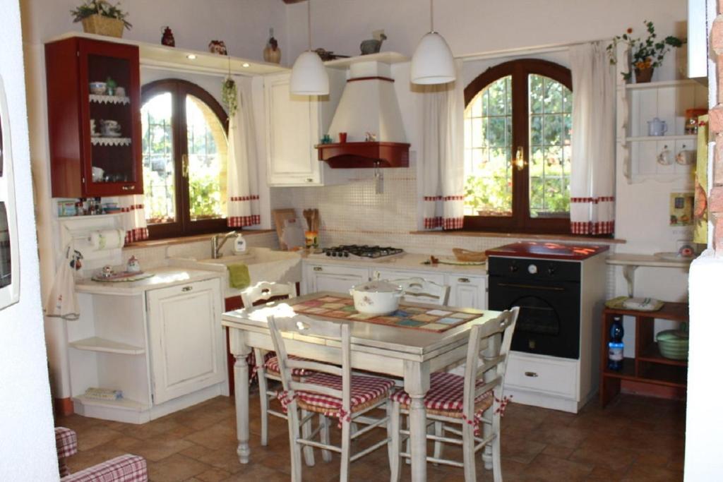 une cuisine avec des placards blancs et une table avec des chaises dans l'établissement Casa Donella, à Poggibonsi
