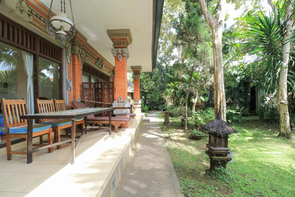 a patio with benches and a table and trees at Rahayu House Ubud in Ubud