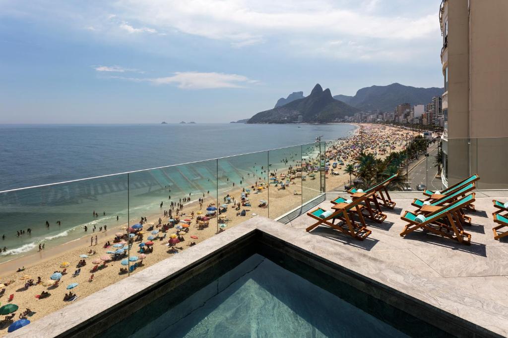 
a beach area with chairs, tables and umbrellas at Hotel Arpoador in Rio de Janeiro
