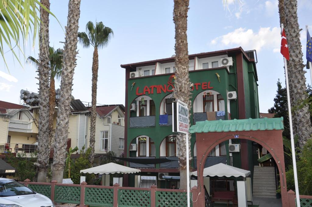 a green building with palm trees in front of it at Latino Hotel in Kemer