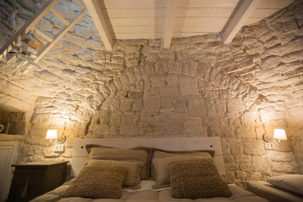 a bedroom with a stone wall with a bed at IL TRULLO DELLA MASSAIA in Alberobello