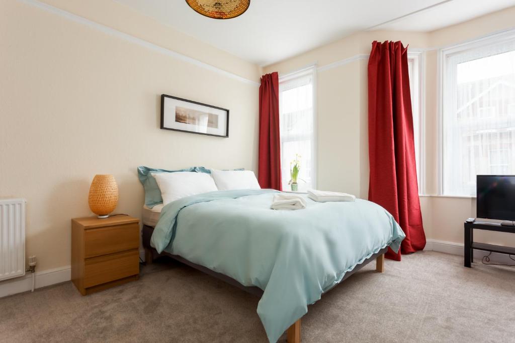 a bedroom with a bed and a tv and red curtains at Stylish Town Centre Apartment Close to Beach and Shops in Bournemouth