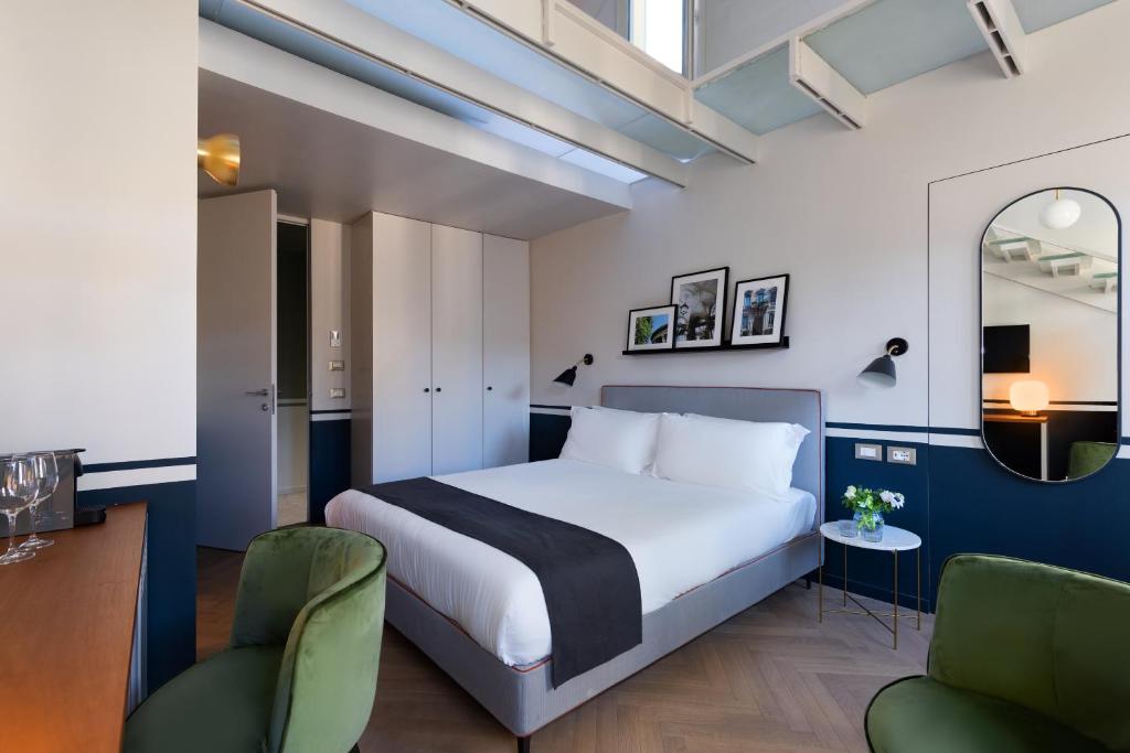 a bedroom with a bed and two chairs and a mirror at Velvet Grey Boutique Hotel in Milan