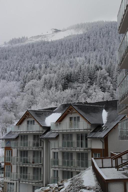 an apartment building in the snow with a mountain in the background at Apartament pod Czarną Górą in Sienna