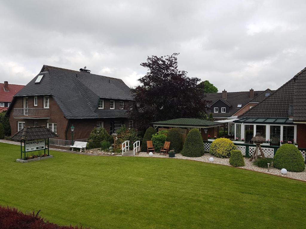 Una casa con un césped verde delante de ella. en Hausnordlicht Dachspitze, en Dornumergrode