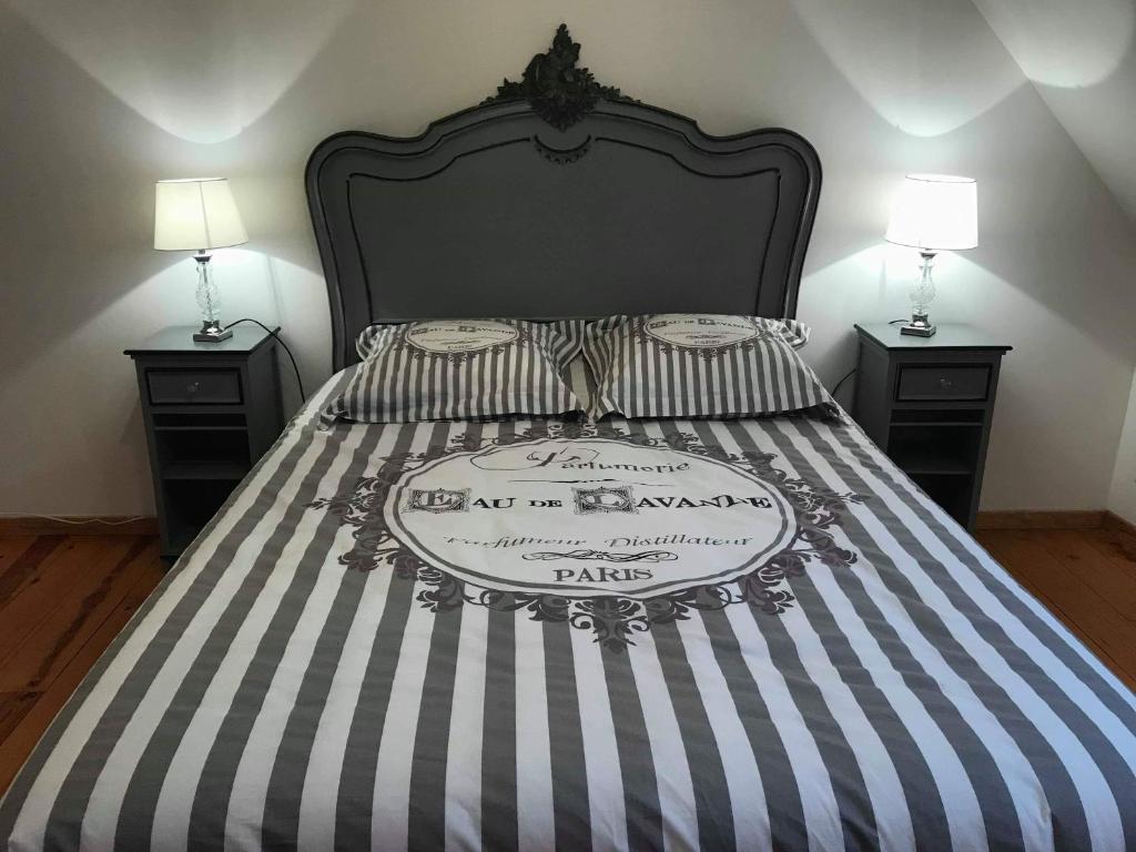 a bed with a black and white striped bedspread and two night stands at la maison de maelys in Courcelles-lès-Gisors