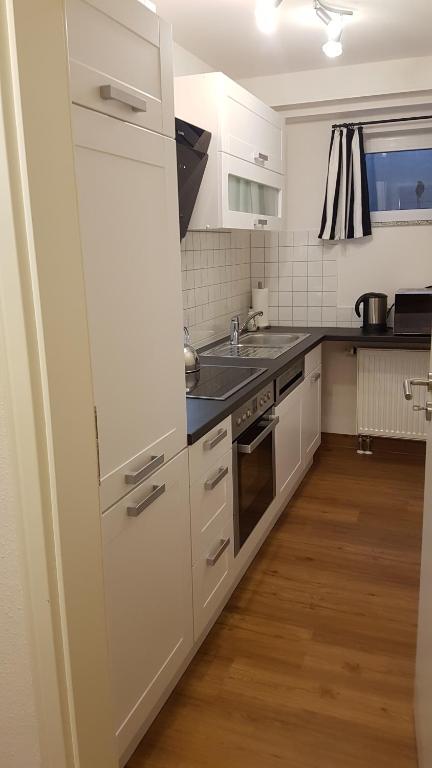 a kitchen with white cabinets and a sink at Ferienwohnung "Waldeck" Nahe Messe und Bodensee in Friedrichshafen