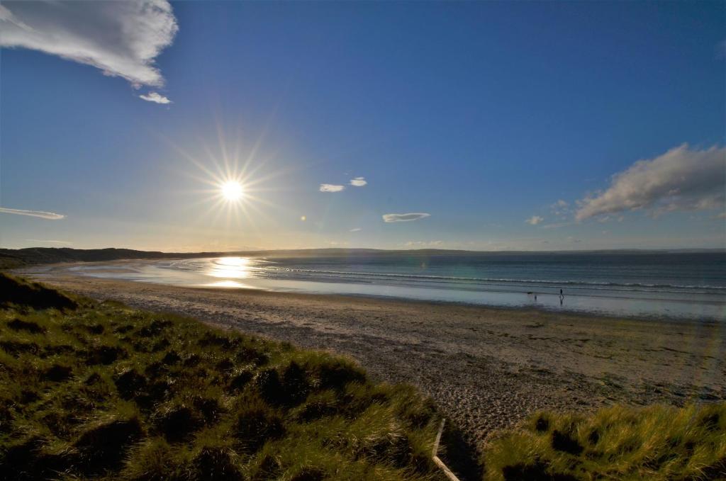 a beach with the sun rising over the ocean at Aurora Bed & Breakfast in Castletown