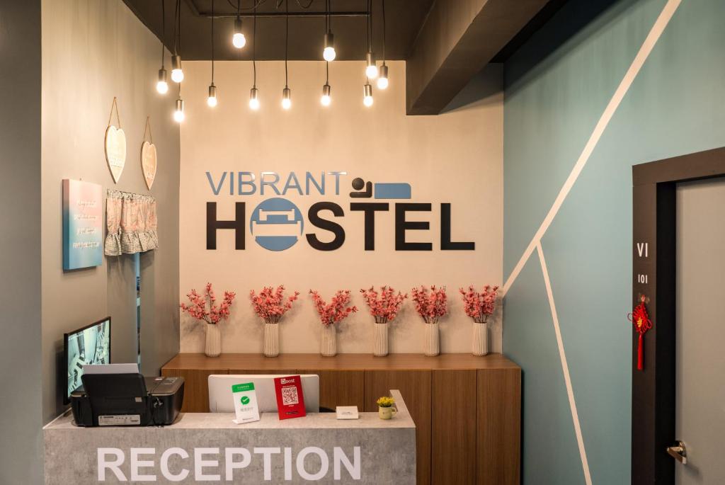 a sign for a veterinary hospital with vases of red flowers at Vibrant Hostel in Kota Kinabalu