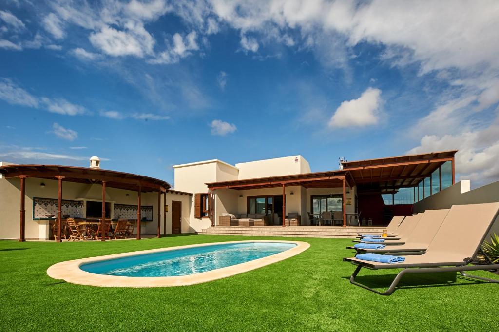 ein Haus mit einem Garten mit Pool in der Unterkunft Las Caletas Village Playa Blanca in Playa Blanca