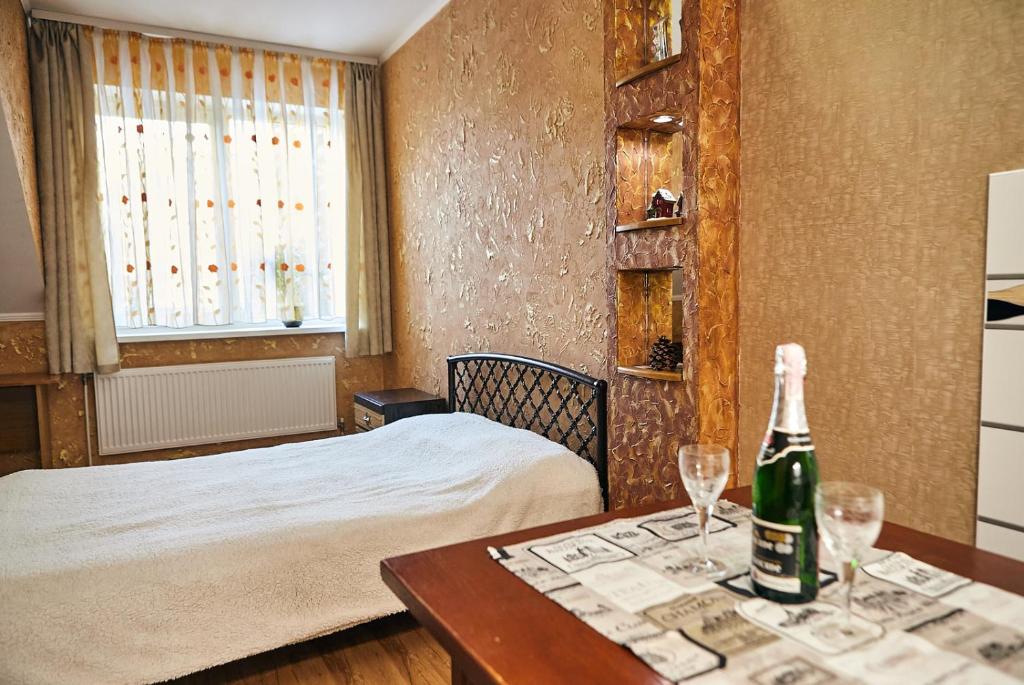 a bedroom with a bed and a bottle of wine on a table at Center Сozy in Vinnytsya