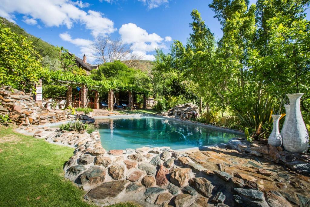 a swimming pool with rocks in a yard at De Poort Country Lodge in Oudtshoorn