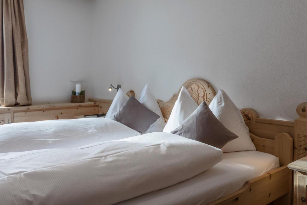 a bedroom with a white bed with white sheets and pillows at Hotel Klarer in Zuoz