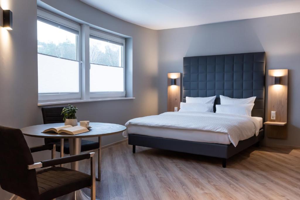 a bedroom with a bed and a table and two windows at Hotel Circle Inn in Ramstein-Miesenbach