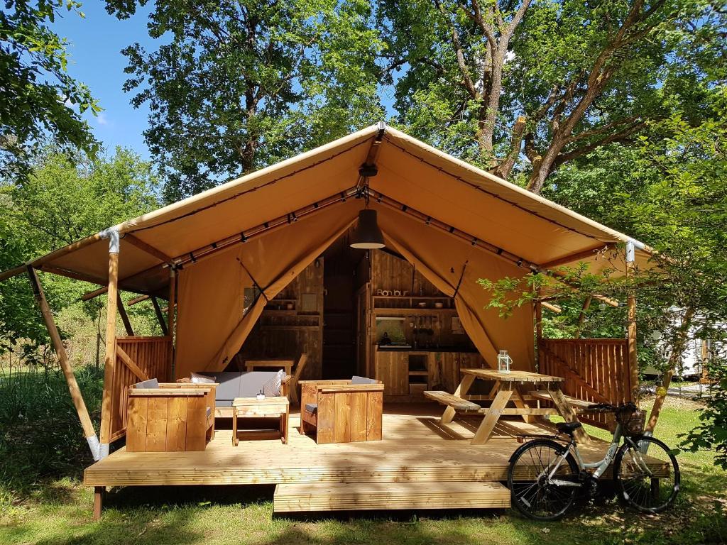 une tente avec une table et un vélo garé dans l'herbe dans l'établissement Camping Bois de St Hilaire, à Chalandray