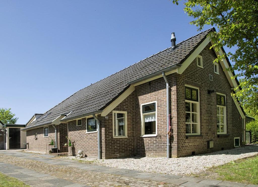 uma casa de tijolos com um telhado de gambrel em Lasca em Schoonoord