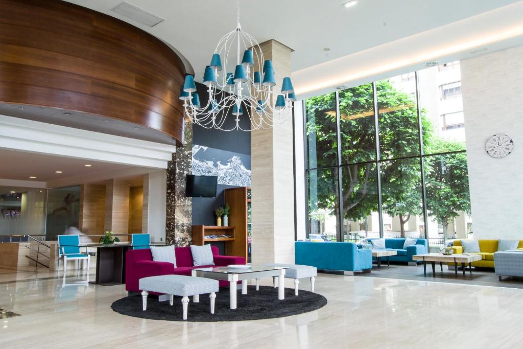 a lobby of a hotel with colorful chairs and tables at Hotel Zentral Gijón Rey Pelayo in Gijón