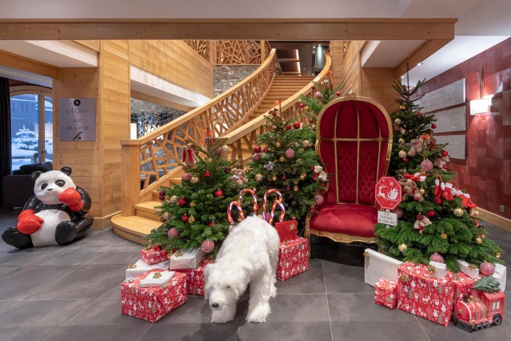 a white dog standing in front of christmas trees at Le Kaïla in Méribel