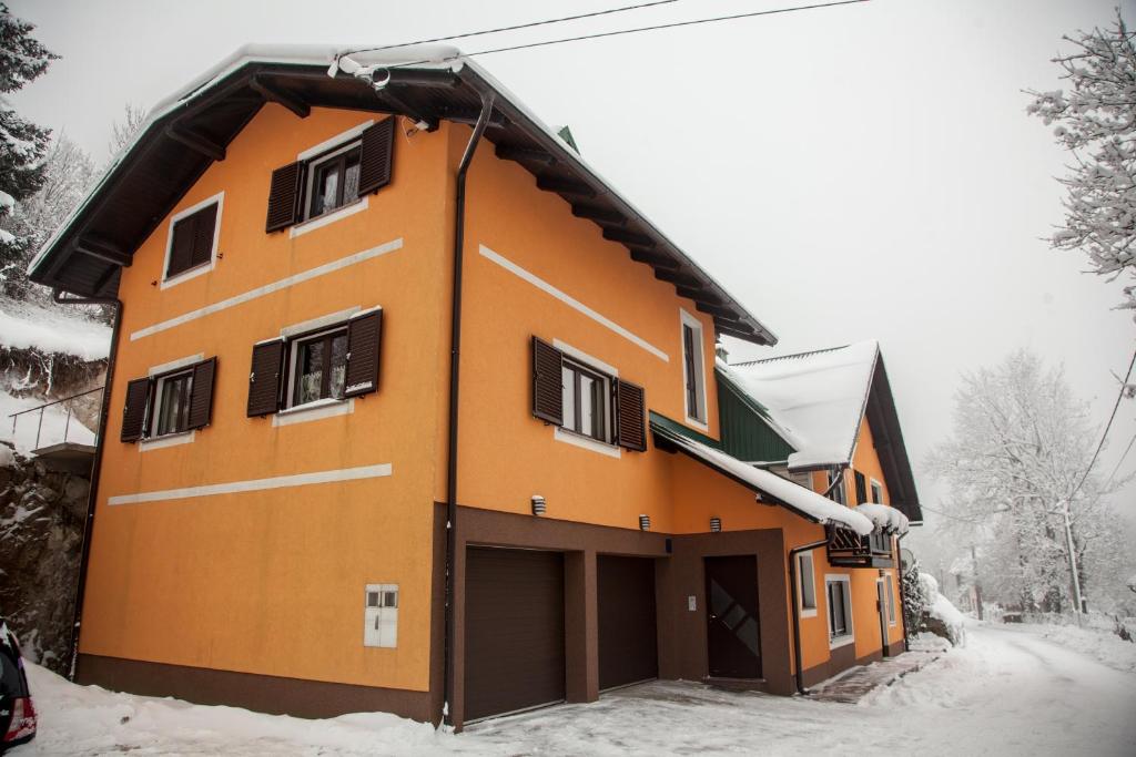 ein orangefarbenes Gebäude mit Schnee auf dem Boden in der Unterkunft Apartmani Kanjer 1 Delnice in Delnice