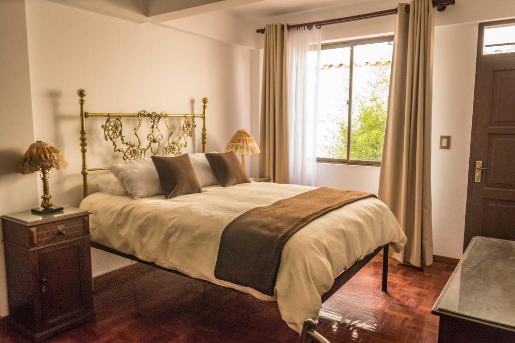 um quarto com uma cama grande e uma janela em El Jardin De Su Merced B&B em Sucre