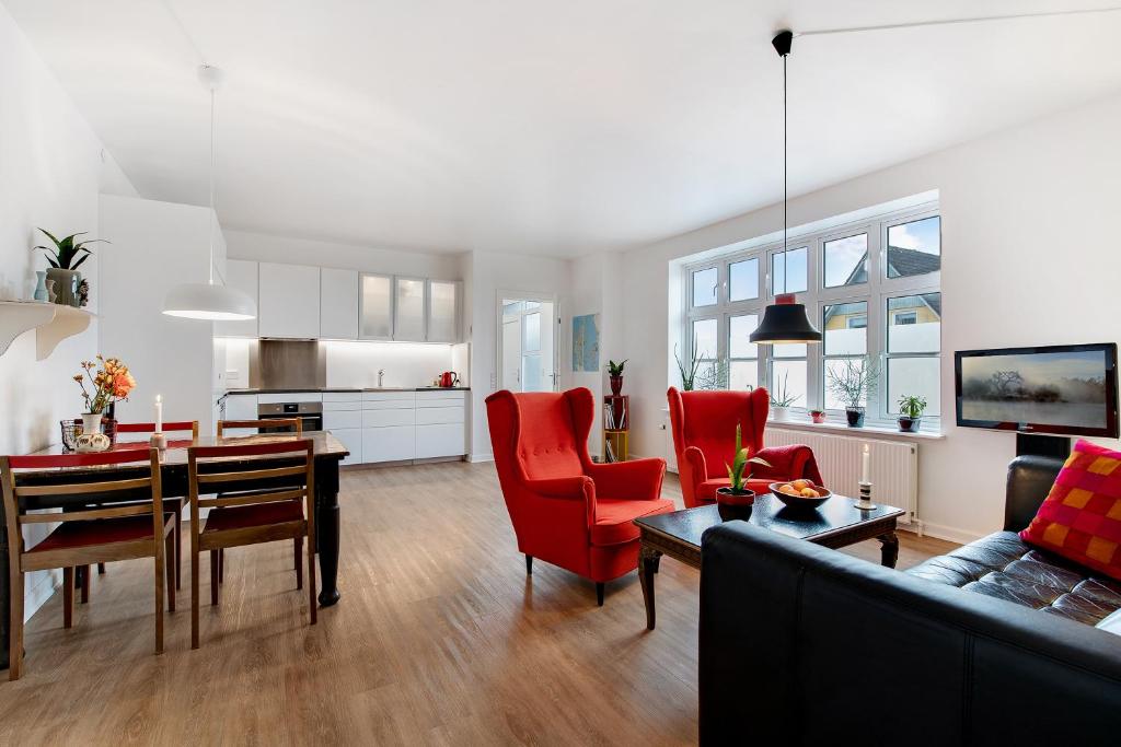 a living room and kitchen with a table and red chairs at Årslev B&B in Randers