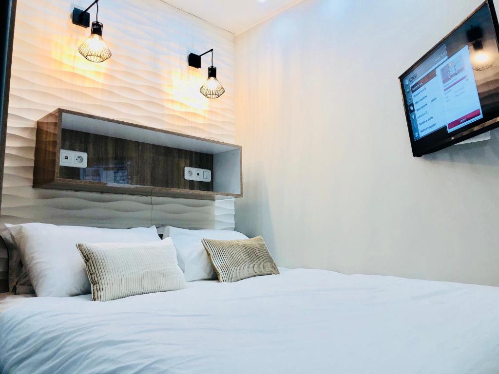 1 dormitorio con 1 cama blanca y TV de pantalla plana en Chambre Love Luxe Monaco en Beausoleil