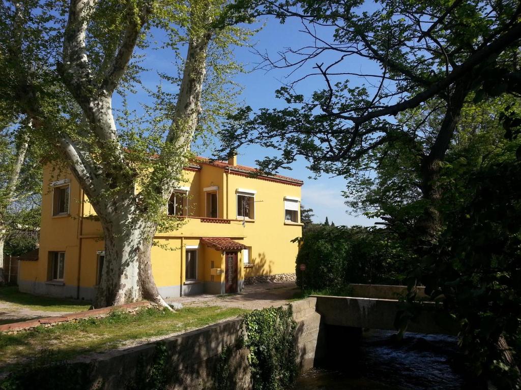 żółty dom z drzewem przed nim w obiekcie Gîte du Mas Arnaud w mieście Thuir