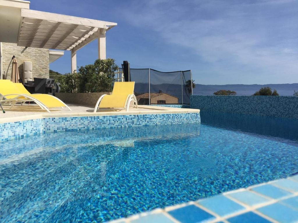 - une piscine avec 2 chaises jaunes à côté d'une maison dans l'établissement Vizzavona Piscine, à Ajaccio