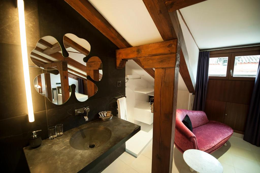 マドリードにあるPosada del León de Oro Boutique Hotelのバスルーム(シンク、ピンクの椅子付)