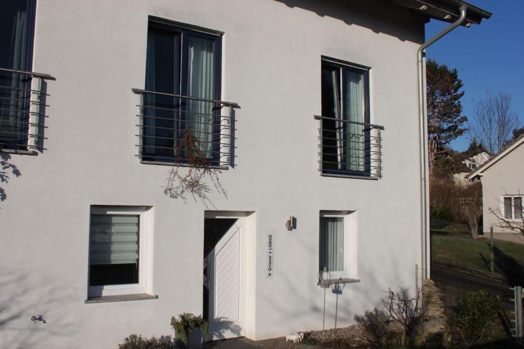 una casa blanca con ventanas negras y una puerta en Grimm's Lodge en Lörrach