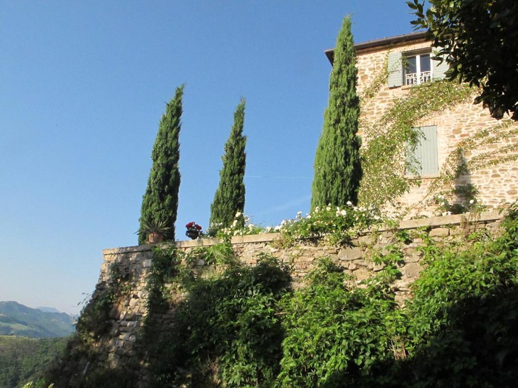 um edifício numa colina com quatro árvores em B&B La Locanda Di Cavoleto em Piandimeleto