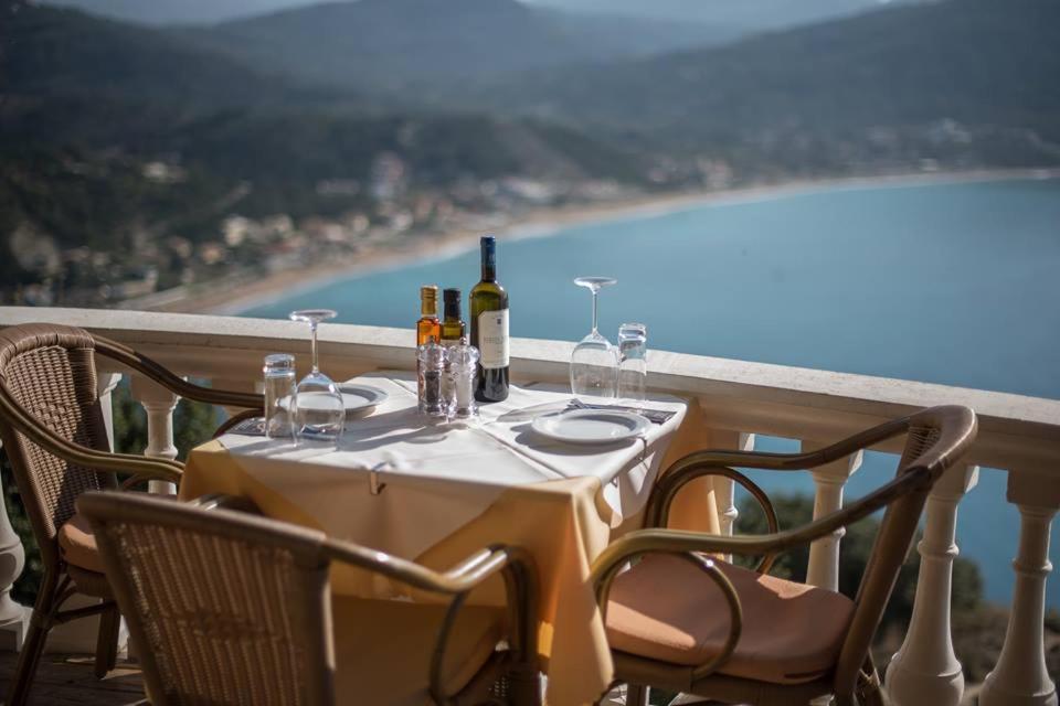 a table with wine bottles and glasses on a balcony at PORTO TIMONI in Afionas