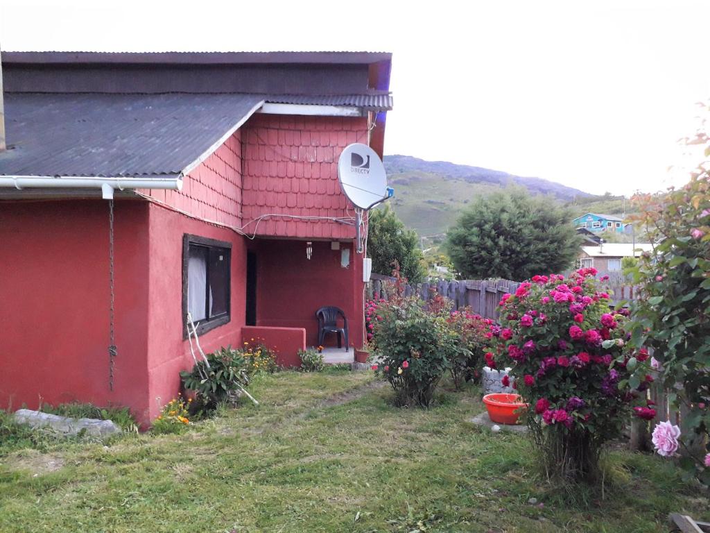 una casa roja en un patio con flores en Hostal y Cabañas Perla del Lago, en Puerto Guadal