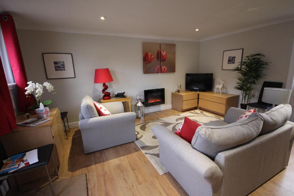 a living room with two couches and a tv at Easter Arr Courtyard Apartment in Nairn