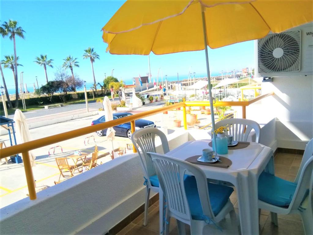 einen Tisch mit gelbem Sonnenschirm und Stühlen auf dem Balkon in der Unterkunft T1 PraiaMar RC com Ar-Condicionado in Quarteira