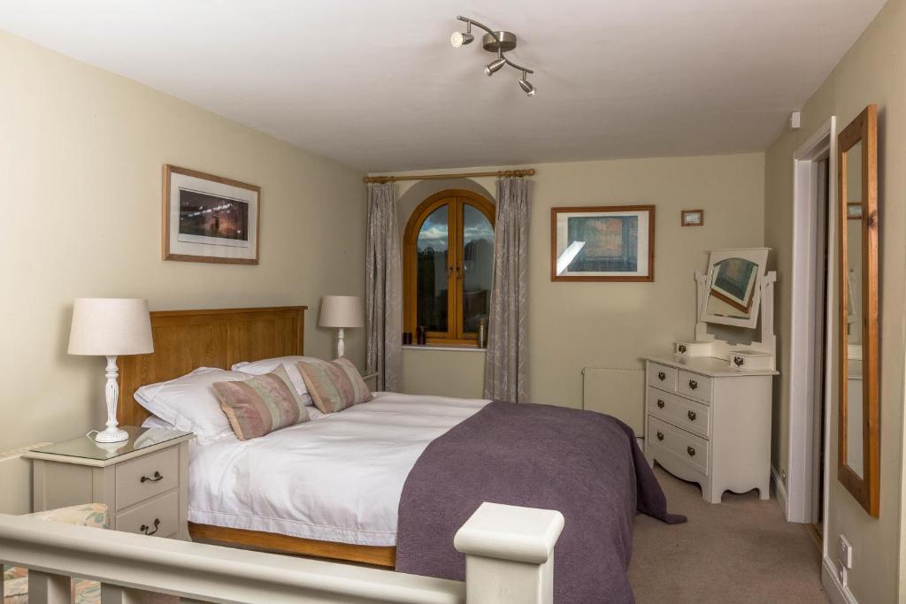 a bedroom with a bed and a dresser at The Dovecote, Stoke Farthing Courtyard in Broad Chalke
