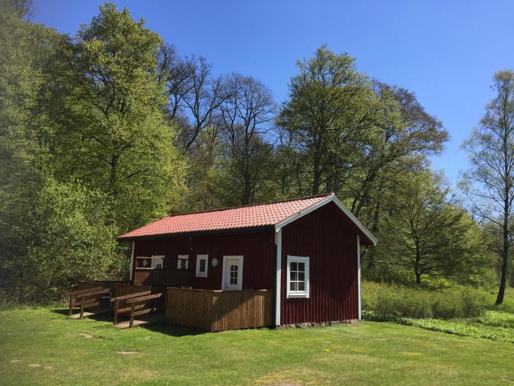 a red cabin in a field with trees at Skäralids Camping & Vandrarhem in Ljungbyhed