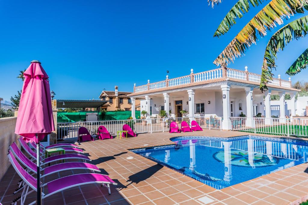 une villa avec une piscine et des chaises roses dans l'établissement Cubo's Villa San Jose, à Alhaurín el Grande