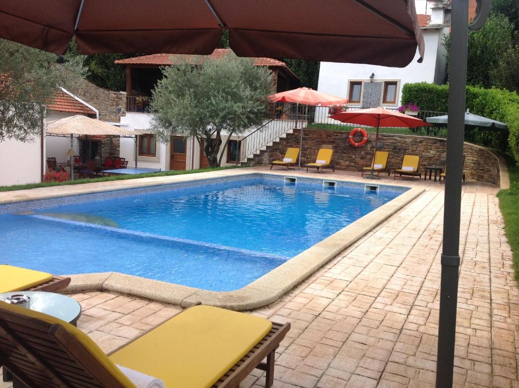 a swimming pool with chairs and an umbrella at Solar de Rabal in Bragança