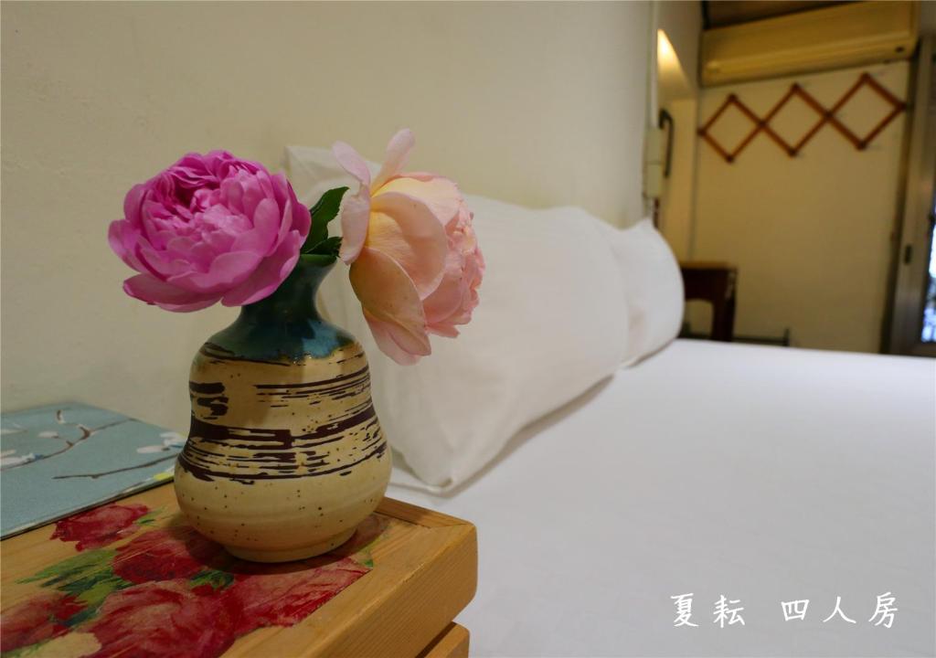 a vase with flowers on a table next to a bed at 玉蟾園民宿 寵物友善 YuChanYuan B&amp;B in Chishang