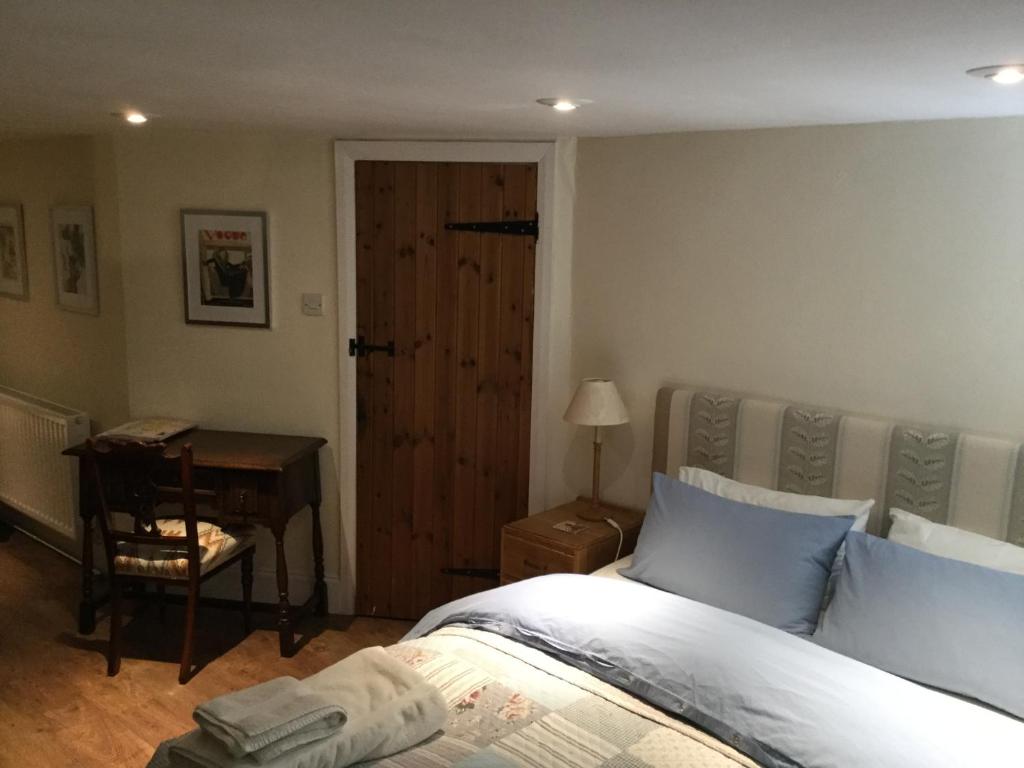 a bedroom with a bed and a desk next to a door at Pear Tree Cottage in Moreton Pinkney