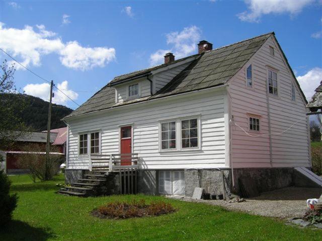a white house with a red door in a yard at Presthus Gård in Ølve
