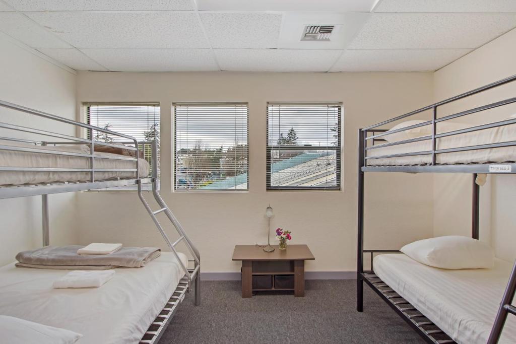 two bunk beds in a room with a table and windows at San Juan Island Hostel in Friday Harbor