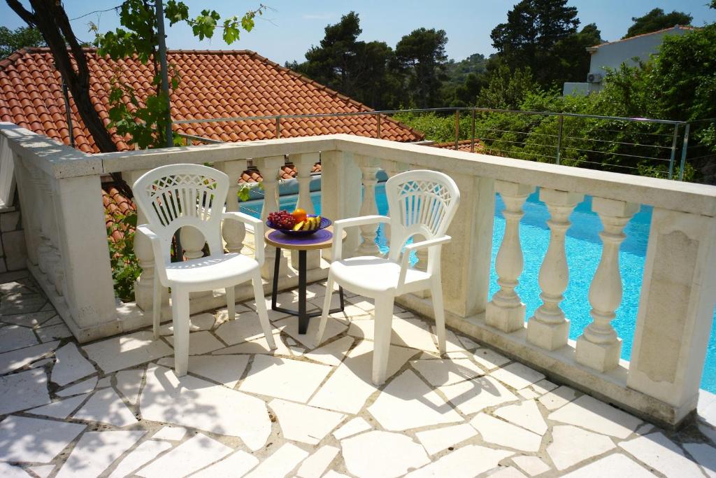 three chairs and a table on a balcony next to a pool at Villa Vinki in Mlini