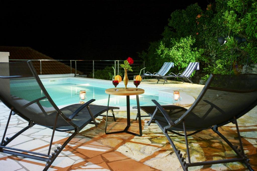a table with glasses of wine on it next to a pool at Villa Vinki in Mlini