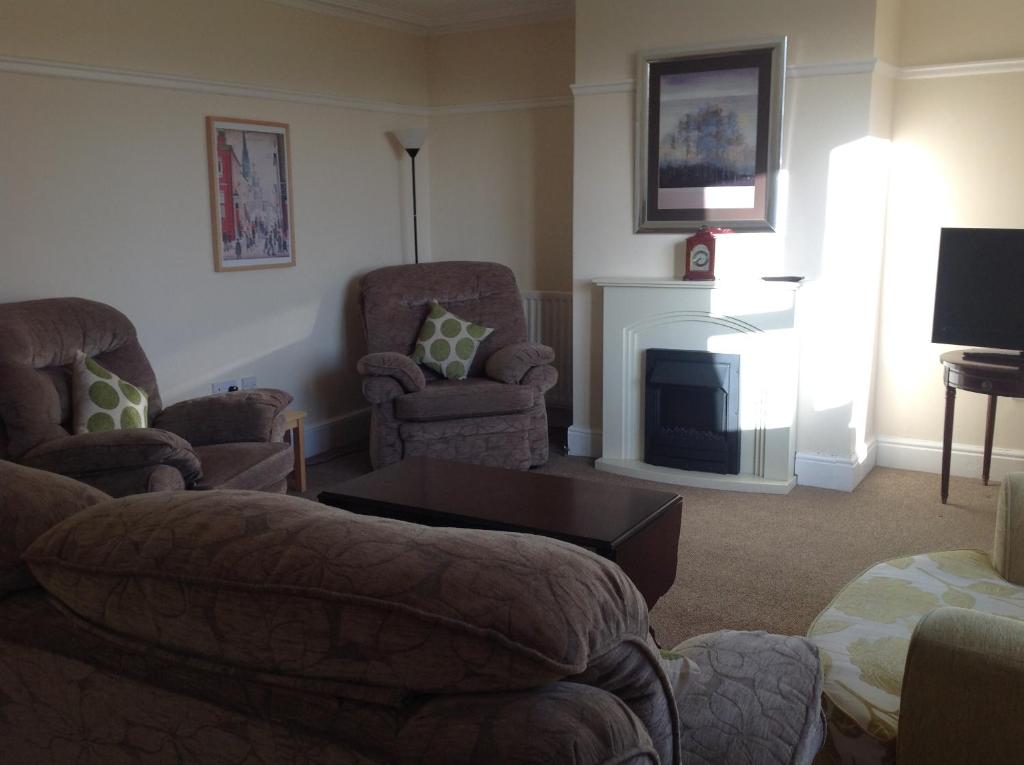 a living room with chairs and a fireplace at Cricket View cottage in Redcar