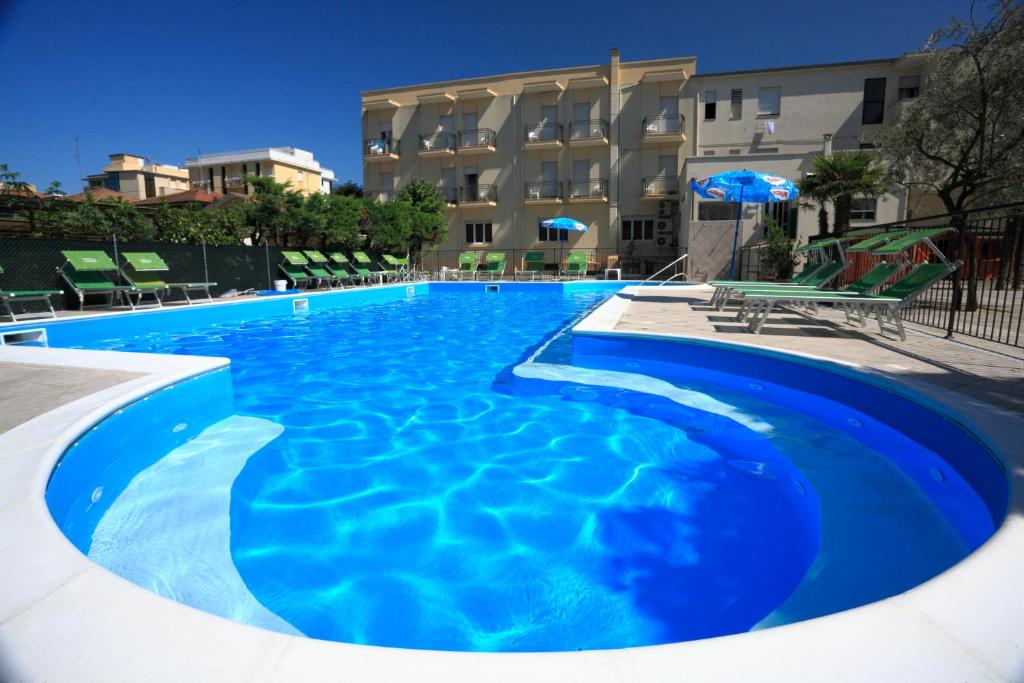 uma grande piscina azul em frente a um edifício em Hotel Vannini em Rimini
